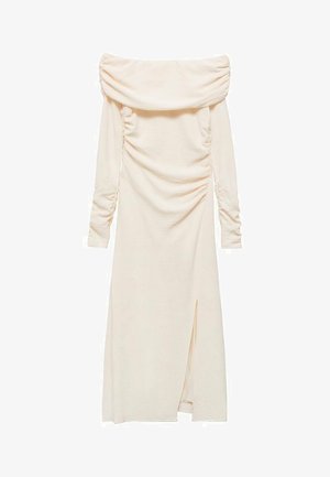 Oblačili brez naramnic, dolgih rokavov iz svetle smetane. Ima naborke na straneh in razporek do stegna na levem boku.