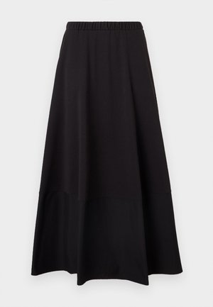 Femme portant une chemise rayée bleu marine à manches longues avec col, rentrée dans une jupe noire taille haute à jambes larges et des sandales noires.