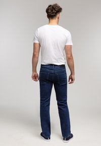 Niebieskie dżinsy o prostym kroju, wykonane z denimu, z klasycznym pięciopocketowym wzorem. Noszone z gładką białą koszulką.