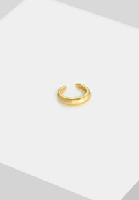 Anillo de metal color oro con un diseño suave y redondeado, con extremos abiertos y una textura pulida.