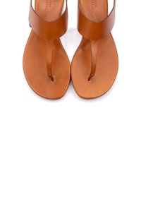 Sandali in pelle tan con un design minimale, dotati di un post per le dita e una fasce larga sopra il piede. Superficie liscia con una suola piatta.
