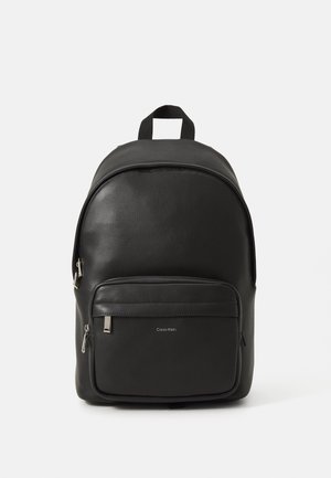 Zaino in pelle nera con parte superiore curvata, tasca anteriore con zip e dettaglio del logo. Presenta spallacci doppi e una finitura strutturata.