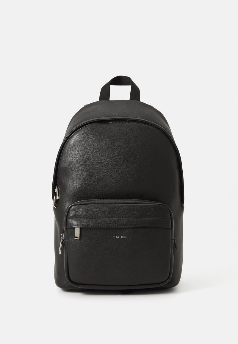 Sac à dos en cuir noir avec un haut arrondi, une poche zippée à l'avant et un détail de logo. Dispose de bretelles doubles et d'une finition texturée.