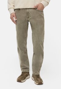 Lyse olivengrønne denimjeans med lige pasform, fem lommer og en subtil, falmet tekstur. Sammen med brune sportssko.