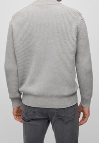 Pull gris en tricot avec texture côtelée, col arrondi et ourlet ajusté. Comprend des manches longues et des coutures détaillées aux épaules.