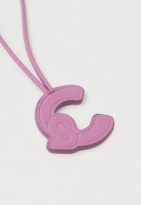 Κρεμαστό κολιέ με μια υφασμάτινη ροζ δερμάτινη γοητεία σε σχήμα μερικού γράμματος "C" σε λεπτό αντίστοιχο ροζ κορδόνι.