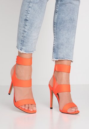 Sandales à talons hauts avec une tige synthétique orange vif, comportant deux larges bretelles traversant le pied et une bride de cheville, design à bout pointu.