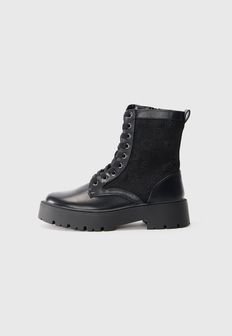 Botte de combat noire à lacets avec semelle épaisse à crampons, motif circulaire perforé sur la partie latérale en daim et accents en cuir.