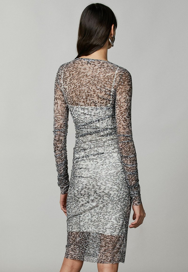 Abito a maniche lunghe, aderente, in tessuto trasparente con un motivo animalier in grigio e beige. Presenta arricciature e un design al ginocchio.