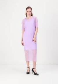 Lilas ribbad stickad klänning med korta ärmar, genomskinlig nedre del och avslappnad passform. Matchad med svarta högklackade skor.