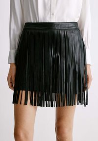 Zwarte leren fringe rok met verticale strepen, knie-lang. Heeft een gladde tailleband en een glanzende textuur, met gelaagde fringe details.