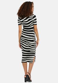 Robe midi rayée noir et blanc avec des manches courtes, fente sur le côté et texture côtelée. Présente une silhouette ajustée et un col rond.