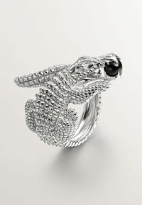 Anillo de plata en forma de serpiente con intrincadas escamas, un diseño enroscado y un ojo de gema negra, que muestra una detallada artesanía y textura.