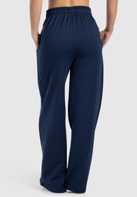Donkerblauwe broek met wijde pijpen, gemaakt van zachte stof, voorzien van een elastische tailleband en zijzakken, met een gladde textuur en een strak ontwerp.