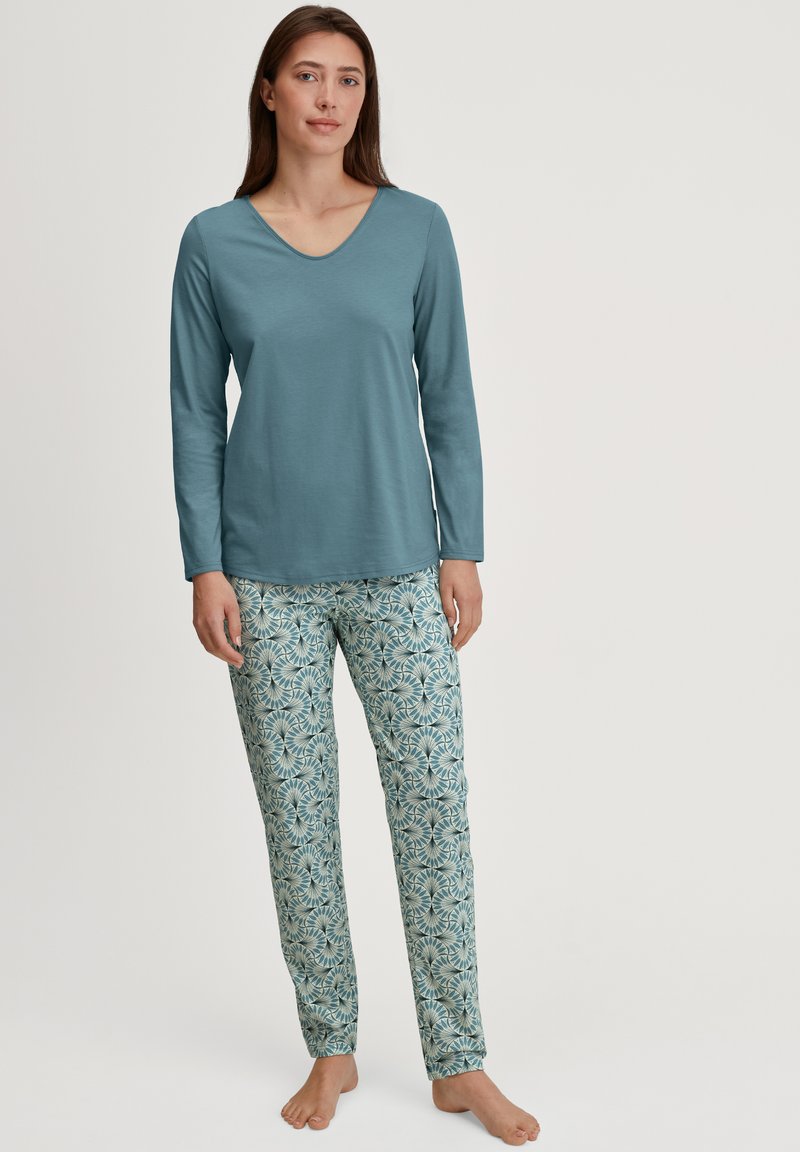Haut teal à manches longues avec un col en V, associé à un pantalon de pyjama léger bleu clair à motifs présentant un design floral en bleu foncé et des accents verts.