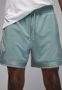 Lyseblå træningsshorts med elastisk talje, snor, sidelommer og en glat, mat overflade.