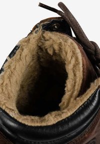 Bota de cuero marrón con cuello negro y grueso forro de lana beige, mostrando la abertura superior y cordones marrones atados en el costado.