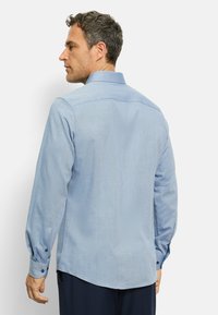 Hellblaues Langarmhemd mit einem subtilen strukturierten Muster, ausgestattet mit einem Kentkragen und knöpfbaren Manschetten. Maßgeschneiderter Schnitt.