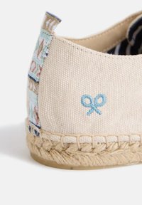 Espadrille de lienzo en beige con bordado azul y suela de yute trenzado. Presenta un ribete estampado en el talón para un detalle adicional.