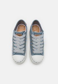 Zilā auduma sporta apavi ar baltām gumijas zolēm, ar pelēkiem šņorēm, korķa iekšzoli un zīmolu uz mēles.