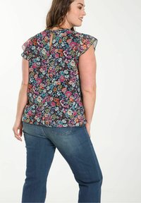 Blomstrete bluse med korte, volangærmer i mørkt stof med flerfarvede blomster. Detalje med nøglehul bagpå, en del af et afslappet outfit.