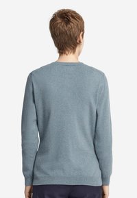 Jasnoniebieski sweter z długimi rękawami, okrągłym dekoltem i miękką fakturą. Charakteryzuje się jednolitą tkaniną, bez wzorów i detali metalowych.