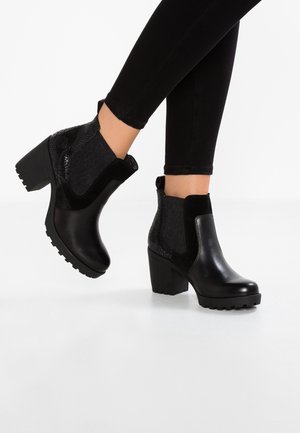 Bottes noires à cheville avec un embout en cuir lisse, des panneaux en tissu texturé et un talon épais avec une semelle crantée.