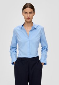 Hellblaue Hemd mit klassischem Kragen, langen Ärmeln und Manschettendetails, kombiniert mit dunkelblauen Hosen. Weicher Stoff.