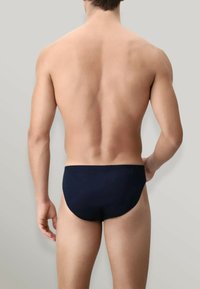 Slip da bagno blu navy con una superficie liscia, vita elastica e un design minimalista, visto da dietro.