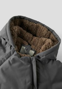Giacca grigia con cappuccio, foderata in morbido pile marrone e dotata di un gancio interno, presentata su uno sfondo chiaro e uniforme.