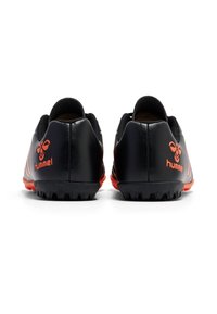 Scarpe sportive nere con accenti rossi, dotate di una tomaia testurizzata, un tallone curvo e tacchetti in gomma pronunciati sulla suola per una maggiore trazione.