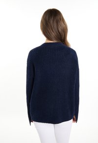 Granatowy sweter dziany o luźnym kroju, prążkowanej teksturze i bocznych rozporkach. Posiada okrągły dekolt, odpowiedni do codziennego użytku.