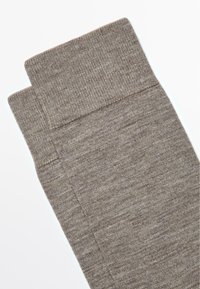 Brune teksturerede sokker med en ribbet kant, lavet af blødt materiale. Stoffet har et diskret meleret mønster og en ensartet vævning hele vejen igennem.