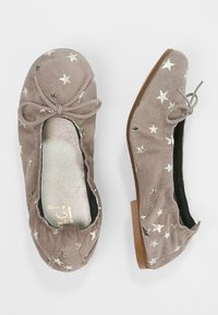Taupe suède balletschoenen met zilveren sterrenpatronen, ronde neuzen, kleine strikjes bovenop en bruine platte zolen.