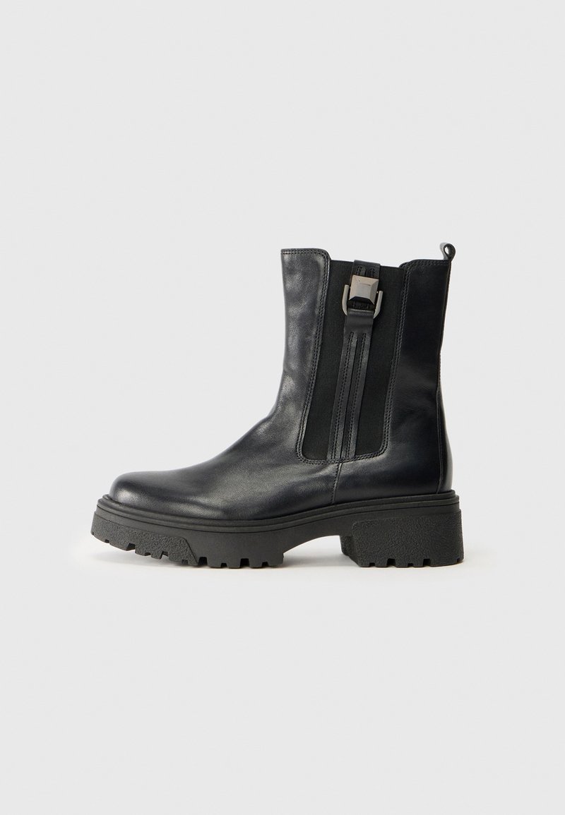 Schwarze Lederknöchelstiefel mit elastischen Seiteneinsätzen, Schnallen-Detail und einer dicken, strukturierten Sohle. Glatte Oberfläche und verstärkter Zugverschluss hinten.