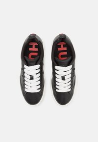 Sneaker in pelle nera con lacci bianchi, colletto imbottito e logo rosso sulle solette, caratterizzati da una texture liscia e design con punta tonda.