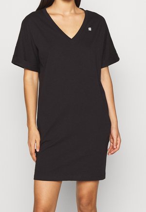 Zwarte V-hals T-shirtjurk van katoen, met korte opgerolde mouwen en een klein logo-accent op de borst. Zachte textuur, losse pasvorm.