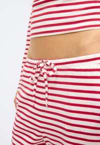 Σετ lounge με κόκκινες και λευκές ρίγες που περιλαμβάνει κορυφή cropped και παντελόνια με ελαστική μέση και κορδόνι. Ομαλό, ελαφρύ βαμβακερό ύφασμα.