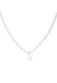 Zilveren ketting met verlengde schakel en een hanger met de letter "M". Gladde textuur en gepolijste afwerking overal.