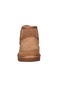 Tan suède enkellaars met een zachte bontvoering. Voorzien van decoratieve stiksels langs de bovenrand en een stevige bruine rubberen zool.