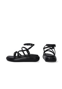 Schwarze Sandalen mit flacher Sohle, die mehrere schmale Riemen über den Fuß und ein Knöchelriemen mit einer Metall-Schnalle zur Anpassung aufweisen.
