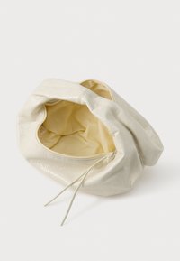 Borsa in pelle morbida e avorio, con un esterno testurizzato, chiusura con zip e un interno in tessuto beige chiaro, che mostra una forma arrotondata e simile a una sacca.