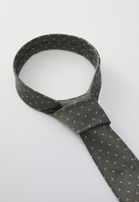 Cravate vert foncé en tissu lisse, ornée d'un petit motif répété de formes roses et crèmes. Design torsadé avec un nœud classique.