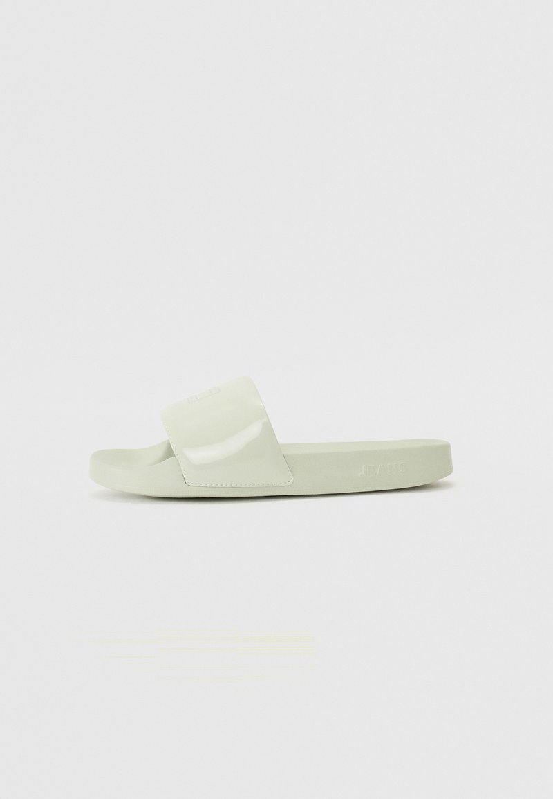 Grønn glidesandal med en blank stropp, en matt såle og minimal merkevare. Har et flatt design med en bred og komfortabel passform.