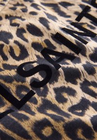 Leopardmuster in Beige und Schwarz mit kräftigen, schwarzen Buchstaben, die in das Design integriert sind. Weiche Textur mit einem dezenten Glanz.