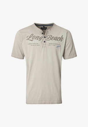 Jasno beżowa koszulka z krótkim rękawem wykonana z bawełny. Posiada trzy guzikową listwę i nadrukowany tekst, w tym "Long Beach" w ciemnym brązie.