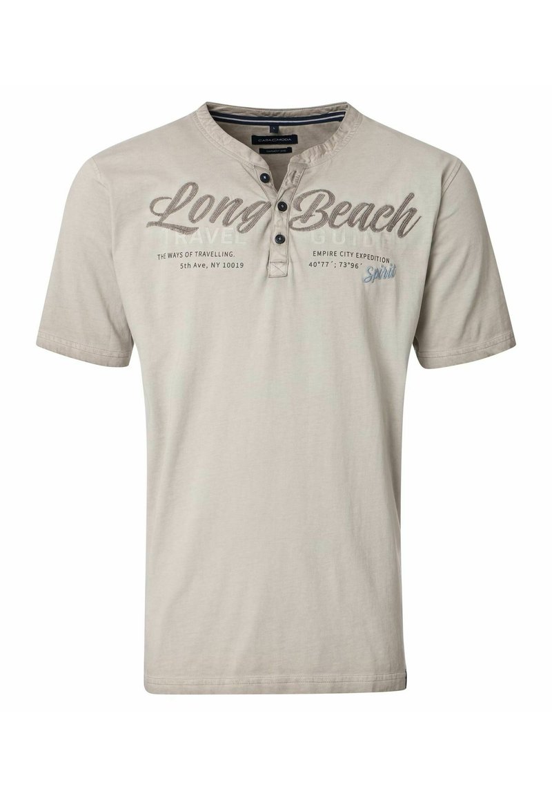 Jasno beżowa koszulka z krótkim rękawem wykonana z bawełny. Posiada trzy guzikową listwę i nadrukowany tekst, w tym "Long Beach" w ciemnym brązie.