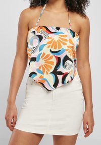 Top de cuello halter multicolor con patrones abstractos florales y geométricos; tejido ligero; combinado con una mini falda blanca.