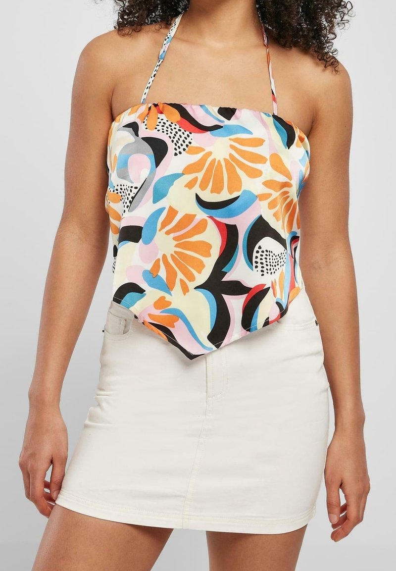 Top de cuello halter multicolor con patrones abstractos florales y geométricos; tejido ligero; combinado con una mini falda blanca.