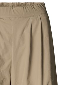 Beżowe szorty z elastycznym pasem, przednimi zakładkami i lekką tkaniną. Posiadają szyte detale oraz małe logo na dolnym boku.